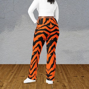 May include: A woman wearing a white long-sleeved shirt and black and orange tiger print leggings.
