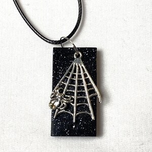 May include: Black and silver glitter necklace with a spider web and spider charm.