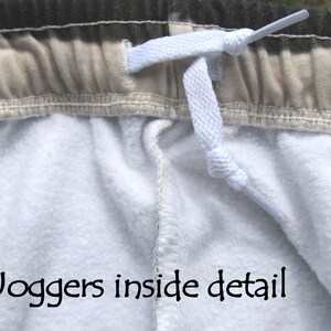 May include: Close-up of the inside of a pair of joggers, showing the white drawstring and the beige waistband. The text "Joggers inside detail" is visible at the bottom of the image.