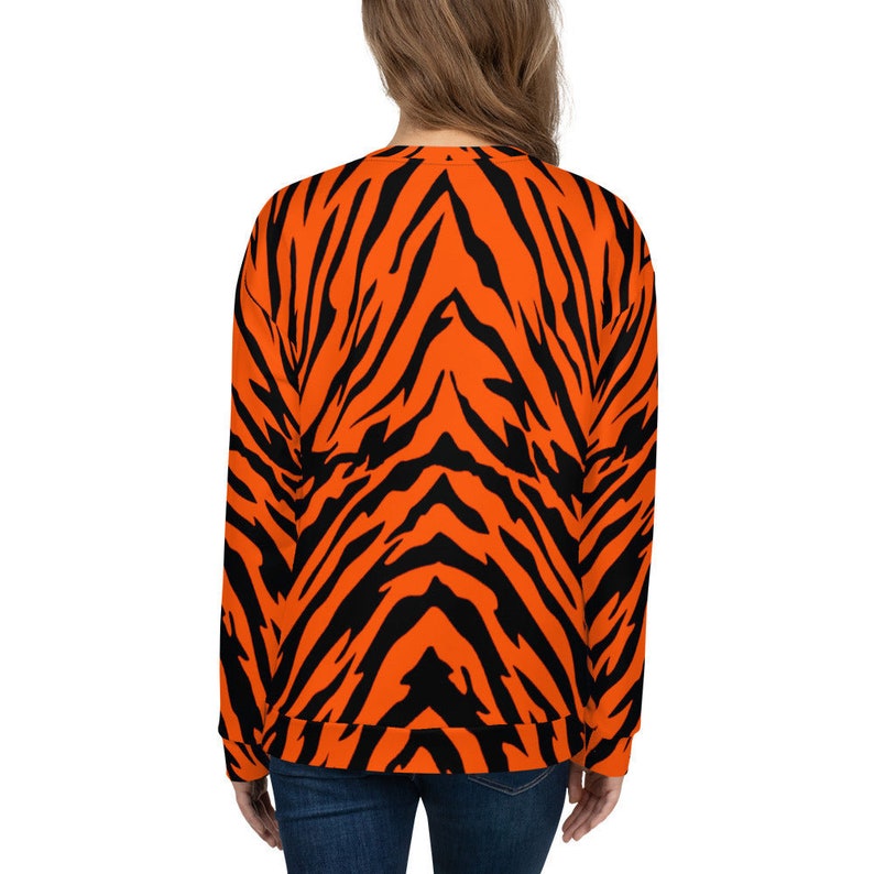 Op de afbeelding: Oranje en zwart gestreept sweatshirt met tijgerprint. Het sweatshirt heeft lange mouwen en een ronde hals.