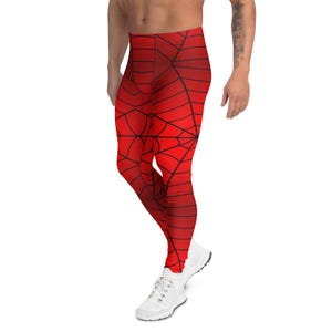 May include: Red leggings with a black spiderweb design. The leggings have a gradient effect, transitioning from a lighter red at the top to a darker red at the bottom. The leggings are paired with white sneakers.