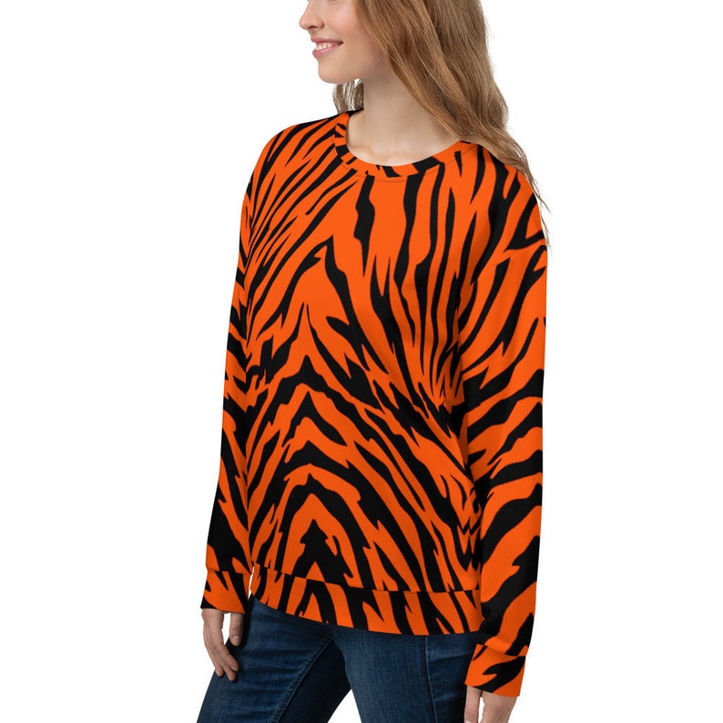 Op de afbeelding: Oranje en zwart gestreept sweatshirt met tijgerprint. Het sweatshirt heeft een ronde hals en lange mouwen.