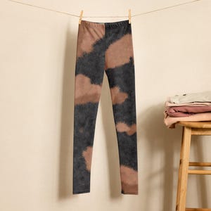 May include: Black and brown tie-dye leggings hanging on a clothesline. The leggings have a faded, abstract pattern.