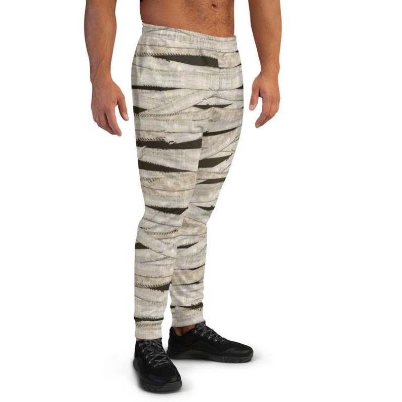 May include: White and brown sweatpants with a mummy-like pattern. The sweatpants have a drawstring waistband and a relaxed fit.