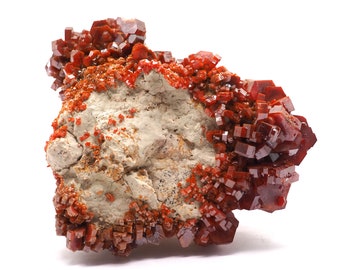 May include: A cluster of red, orange, and brown crystals on a gray rock. The crystals are sharp and have a glassy appearance.