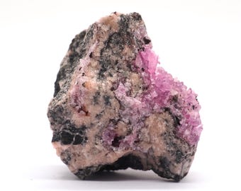 May include: A rough, gray and pink rock with pink crystals embedded in it. The rock is about the size of a fist.