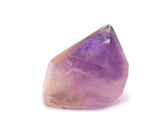 May include: A polished amethyst crystal with a faceted top and a natural, rough base. The crystal transitions from a pale, translucent lavender to a deep, rich purple hue. The stone is displayed against a clean white background.