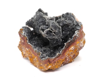 May include: A geode with a dark gray crystal interior and a reddish-brown and yellow exterior. The crystals are clustered together, creating a textured surface. The geode is a natural mineral formation.