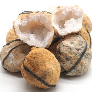 May include: A group of geode crystals with a rough, brown exterior and a white, crystalline interior. Some of the geodes are broken open, revealing the sparkling crystals inside.