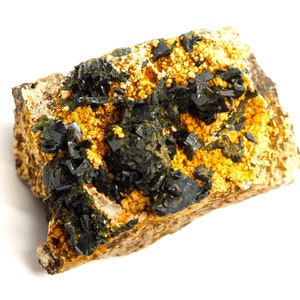 May include: A mineral specimen featuring a matrix of tan rock with clusters of small, golden-yellow crystals. Dark, black, crystalline structures are interspersed throughout, creating a striking contrast. The overall composition suggests a natural, geological formation.