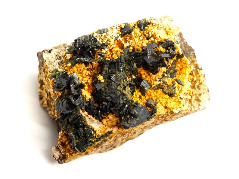 May include: A mineral specimen featuring a matrix of tan rock with clusters of small, golden-yellow crystals. Dark, black, crystalline structures are interspersed throughout, creating a striking contrast. The overall composition suggests a natural, geological formation.