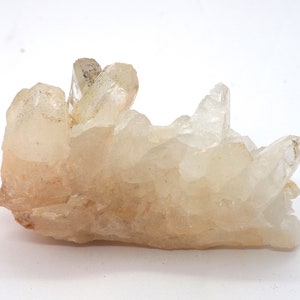 Peut inclure: Un amas de cristaux de quartz transparents avec une teinte blanc laiteux. Les cristaux sont regroupés dans une formation naturelle, créant une forme unique et intéressante.