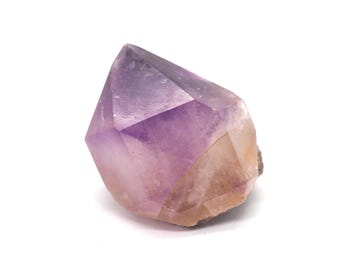 May include: A faceted amethyst crystal with a gradient of colors, transitioning from a deep purple at the top to a light tan at the base. The crystal is set against a white background, highlighting its natural beauty.