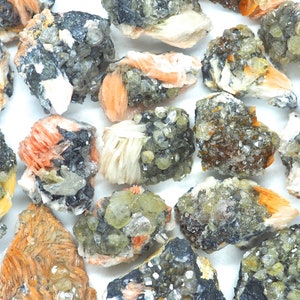 Puede incluir: Una colección de cristales en bruto sin pulir de varios colores, incluyendo naranja, blanco y verde. Los cristales están agrupados y tienen una textura rugosa y natural.