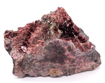 May include: A raw mineral specimen featuring a mix of colors. The base rock is a dark gray with patches of pink and purple. The top of the specimen is covered in clusters of deep red crystals, with hints of green.