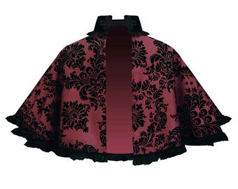 May include: A burgundy velvet cape with a black damask pattern and black lace trim. The cape has a high collar and a back closure.