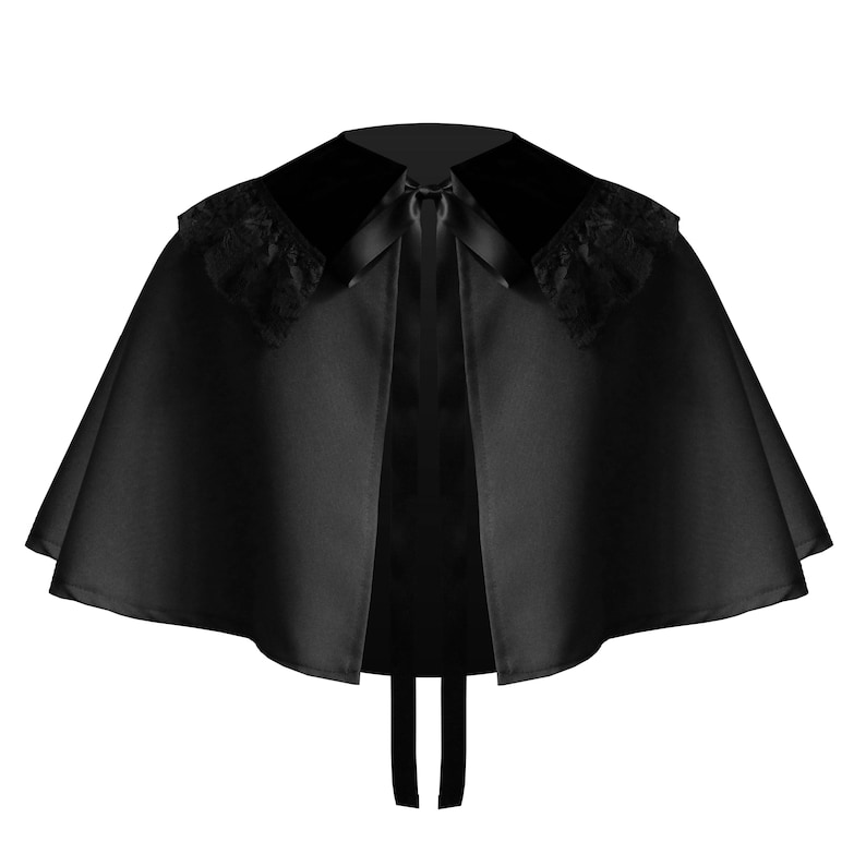 May include: A black capelet featuring a smooth satin-like fabric, a wide collar with black lace trim on the shoulders, and a thin black ribbon tie closure at the center front. The garment has a flared, circular silhouette that drapes evenly.