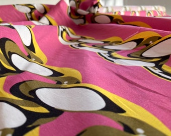 Puede incluir: Tela rosa con un patrón repetitivo de formas abstractas blancas, amarillas y marrones. La tela tiene una textura suave y sedosa.