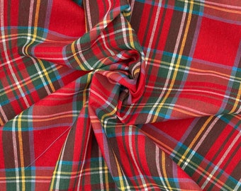 May include: Red plaid fabric with a multi-colored plaid pattern. The fabric is folded and draped, showing the texture and weave of the material.