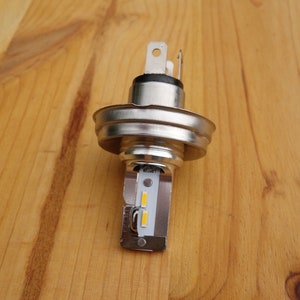 May include: A silver LED light bulb with a white and yellow LED strip. The bulb has a standard base and is designed for use in a car or other vehicle.