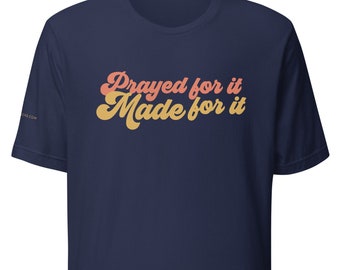 May include: Navy blue t-shirt with the text "Prayed for it Made for it" in a retro font with orange and yellow color gradient.