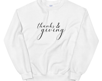 May include: White sweatshirt with the text "thanks & giving" in black script font.