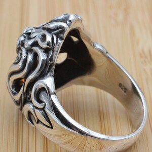 May include: A detailed sterling silver ring with an ornate design. The ring features a sculpted lion's head with intricate detailing and a polished finish. The band is marked with "925".