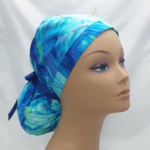 May include: A blue and green patterned surgical scrub hat with a blue ribbon tie. The hat is made of a soft, comfortable fabric and is designed to be worn by medical professionals.