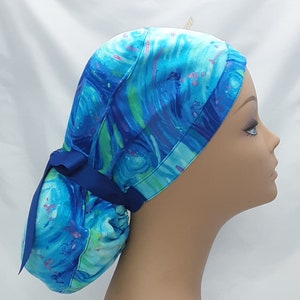 May include: A blue and green patterned surgical scrub hat with a blue ribbon tie. The hat is made of a soft, comfortable fabric and is designed to keep hair out of the way during surgery.