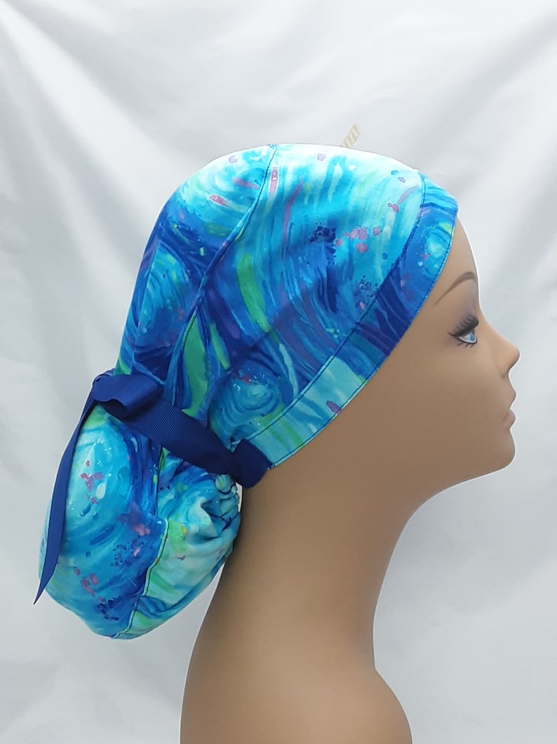 May include: A blue and green patterned surgical scrub hat with a blue ribbon tie. The hat is made of a soft, comfortable fabric and is designed to keep hair out of the way during surgery.