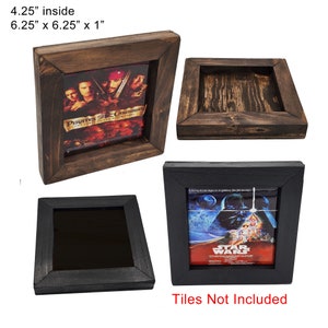 May include: Two wooden picture frames with a dark brown finish. The frames are 6.25 inches by 6.25 inches and 1 inch thick. The inside of the frame is 4.25 inches. One frame has a Pirates of the Caribbean movie poster inside and the other frame has a Star Wars movie poster inside. The text "Tiles Not Included" is printed below the frames.