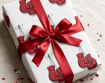 May include: A rectangular gift box wrapped in white paper featuring a repeating pattern of red boxing gloves. The package is tied with a wide, smooth, dark red satin ribbon that is tied into a large, centered bow on the top surface.