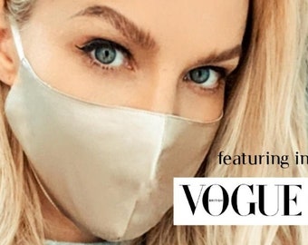 May include: A woman wearing a light beige satin face mask. The mask has a smooth, silky texture. The text "featuring in VOGUE" is visible in the lower right corner of the image.