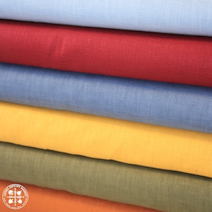 May include: A stack of six fabric swatches in different colors, including blue, red, yellow, green, and brown. The swatches are folded and layered on top of each other. The fabric appears to be linen.