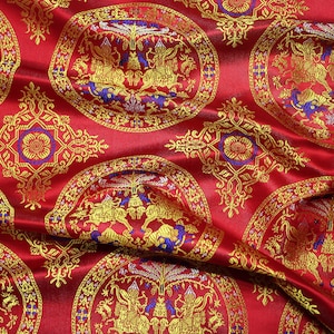 May include: Red fabric with a repeating pattern of gold and blue circular designs. The centre of each circle features a stylised image of a mythical creature.