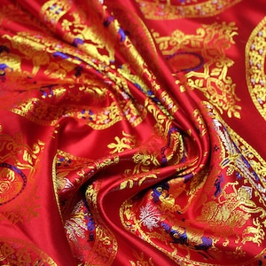 May include: Red fabric with a gold and blue brocade pattern. The pattern features repeating circular designs with intricate details.