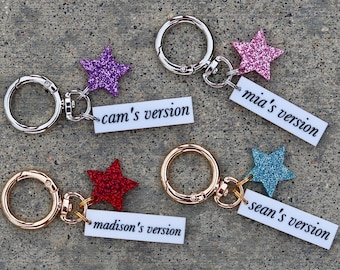 May include: Four keychains with metal lobster clasps, each featuring a glittery star charm and a white rectangular tag. The tags are printed with the black text cam's version, mia's version, madison's version, and sean's version respectively.
