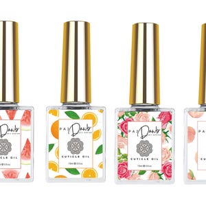 May include: Four clear glass bottles with gold lids and labels. Each bottle contains cuticle oil and features a different fruit design: watermelon, orange, roses, and peaches. The labels read "PAZ Dawb Nail Boutique" and "CUTICLE OIL 11ml/0.37oz".