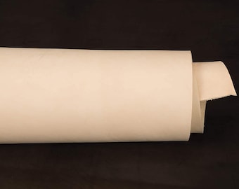 May include: A roll of off-white leather, rolled up and lying on a black surface.