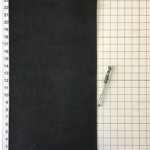 Może przedstawiać: Czarny arkusz pianki o wymiarach około 56 cm x 30 cm, umieszczony na powierzchni siatkowej.