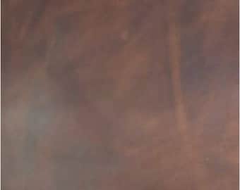 May include: A close-up of a brown leather surface with a subtle, mottled texture.