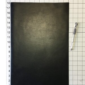 Może przedstawiać: Czarny arkusz sk&oacute;ry o wymiarach 30,5 cm x 38,1 cm. Sk&oacute;ra ma subtelny połysk i fakturowaną powierzchnię.