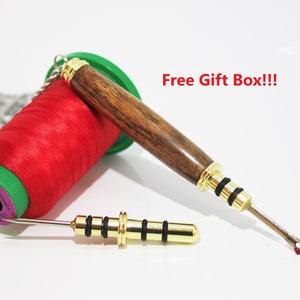 May include: A red spool of thread with a green base, a wooden seam ripper, and a gold-colored seam ripper. The seam rippers have gold accents. The text "Free Gift Box!!!" is in the image.