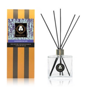 May include: A glass bottle reed diffuser with a gold cap and black reeds. The bottle has a label that says "RAINIER'S GIFTS CELEBRATE LIFE LAVENDER ESCAPE REED DIFFUSER | DIFFUSEUR DE PARFUM 6.5 fl oz e 192 ml."