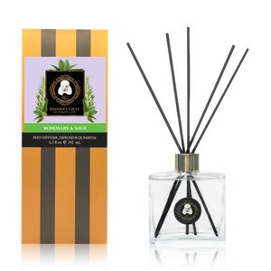 May include: A clear glass bottle with a gold lid and black reeds, filled with a reed diffuser. The bottle has a label that says "Rainier's Gifts Celebrate Life" and "Rosemary & Sage". The label also says "Reed Diffuser | Diffuseur de Parfum 6.5 fl oz e 192 ml."