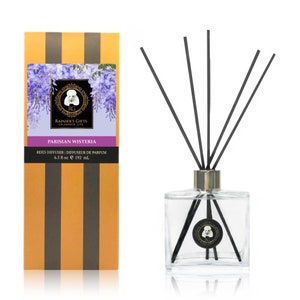 May include: A glass bottle with black reeds and a gold cap filled with a clear liquid. The bottle has a label that says "Parisian Wisteria" and "Rainier's Gifts Celebrate Life". The label also says "Reed Diffuser | Diffuseur de Parfum 6.5 fl oz e 192 ml".