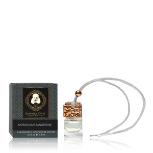 May include: A small glass bottle with a gold-colored cap and a silver string hanging from it. The bottle is filled with a clear liquid and is labeled "Moroccan Tangerine" car diffuser. The bottle is packaged in a black box with a gold-colored logo and the text "Rainier's Gifts Celebrate Life".