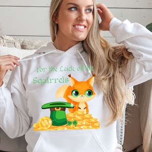 May include: White hoodie with a green shamrock and a cartoon squirrel wearing a green hat. The text on the hoodie says "For the Luck of the Squirrels".