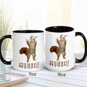 May include: Two white ceramic mugs with black rims and handles. Both mugs feature a cartoon squirrel with the word "squirrel!" printed below. The mug on the left is 11 oz and the mug on the right is 15 oz.