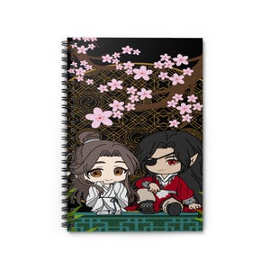 Puede incluir: Una libreta de espiral con fondo negro que presenta dos personajes de anime sentados bajo un cerezo en flor. Los personajes llevan ropa tradicional china. El fondo está decorado con patrones geométricos dorados y negros.